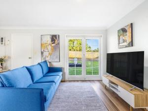 a living room with a blue couch and a tv at Great value Stylish 2BR Granny Flat Heritage Park in Boronia Heights