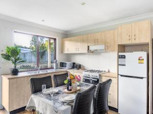 een keuken met een tafel met stoelen en een witte koelkast bij Great value Stylish 2BR Granny Flat Heritage Park in Boronia Heights