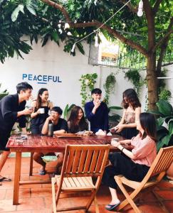 um grupo de pessoas sentadas em torno de uma mesa de madeira em Peaceful house em Vung Tau