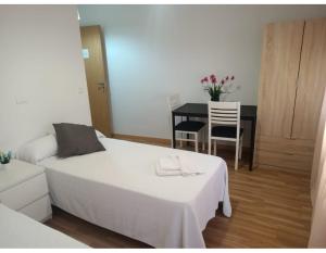Un dormitorio con una cama y una mesa y sillas. en Pilgrim Rooms, en Redondela