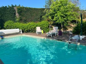 una piscina con due sedie e una panchina di Maison d'Hôtes L'Escale Du Loup Blanc a Maringes