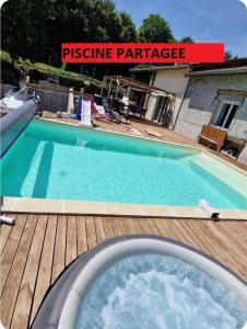 a swimming pool on a wooden deck next to a house at Détente en Pays d'Urfé in Saint-Marcel-dʼUrfé