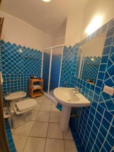 Baño de azulejos azules con aseo y lavamanos en Bellavista Holiday Home en San Pasquale