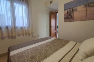een slaapkamer met een bed met een schilderij aan de muur bij Apartamento Conil Centro y Playa, San Sebastian in Conil de la Frontera