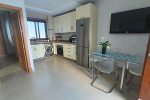 een keuken met een tafel, een koelkast en een magnetron bij Apartamento Conil Centro y Playa, San Sebastian in Conil de la Frontera