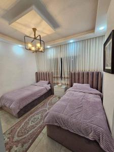 a bedroom with two beds and a chandelier at Jordan home in Irbid