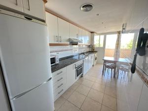 eine Küche mit einem weißen Kühlschrank und einem Tisch in der Unterkunft Relax Nou Fontana 200M2 5min Beach in Jávea