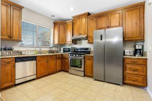 a kitchen with wooden cabinets and a stainless steel refrigerator at Designer house with balcony, 9 mins to Disneyland in Fullerton