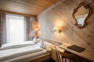 una camera da letto con un letto e una scrivania con uno specchio di Hotel Digon a Ortisei