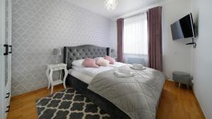a bedroom with a bed with pink pillows on it at Apartamenty Sun & Snow Nadmorskie in Sopot