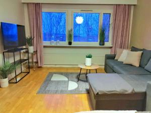 a living room with a couch and two windows at Mesikämmen - Free parking & WiFi - Next to the forest - Rating 9,4 in Jyväskylä