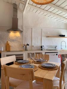 a kitchen with a wooden table with plates and wine glasses at Casa da Barrada-Monsaraz in Monsaraz