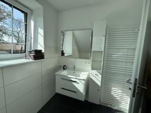 a white bathroom with a sink and a mirror at Ferienwohnung Berta auf Höpers Wohnpark in Winsen Aller