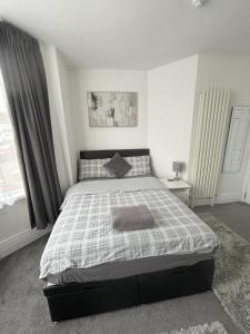 a bedroom with a bed with a checkered blanket at Copperfield Homestay in Cardiff