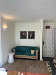 - un canapé vert dans le salon avec deux photos sur le mur dans l'établissement MORO Marrakech Boutique Hôtel, à Marrakech