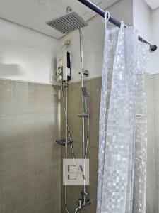 een douche met een douchegordijn in de badkamer bij k~crib at Shore Residences Tower A, MOA Complex in Manilla