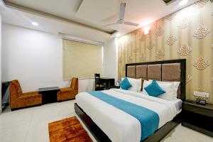a bedroom with a large bed and a chair at De Atlantis Inn Hotel Near Delhi Airport in New Delhi