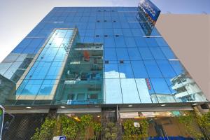De Atlantis Inn Hotel Near Delhi Airport في نيودلهي: مبنى زجاجي طويل مع نوافذه تعكس السماء