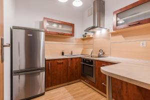 a kitchen with a stainless steel refrigerator and wooden cabinets at Apartament Fregata in Gdańsk
