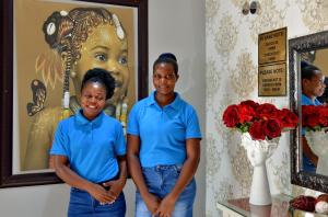 dos mujeres con camisas azules de pie frente a una pintura en The Shore House, en Hartbeespoort