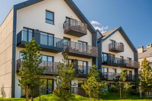 an apartment building with balconies and trees at Apartament SUNSET SurfingBird Dźwirzyno in Dźwirzyno