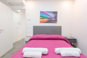 una camera con letto rosa e un dipinto sul muro di Mascarella Apartments a Bologna