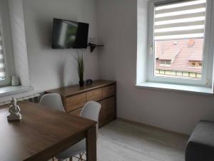 a dining room with a table and a television on a wall at Apartament Alma in Srebrna Góra