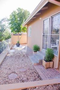 eine Terrasse mit einem Tisch und Stühlen vor einem Haus in der Unterkunft Neat & New Private 2 bedroom Backyard Flat. in Windhoek
