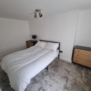 a bedroom with a bed with white sheets and a light at Quite central flat in Plymouth