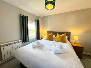 a bedroom with a large white bed with yellow pillows at The Coppersmith - Warehouse Apartments, Lake District in Ulverston