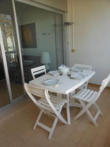a white dining room table with two white chairs at APPT 2 PIECES 52m² + LOGGIA 7m² REF 4023 in Le Castellas