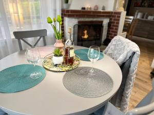 een witte tafel met twee wijnglazen en een open haard bij Domek Kamień in JeleÅ„ska Huta