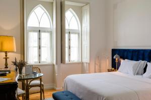 a bedroom with a bed and a desk and two windows at Torres da Vila in Anadia +31 photos