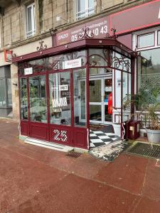a red storefront with a checkered sidewalk in front at Enzo Hotels Limoges Centre Jourdan by Kyriad Direct in Limoges