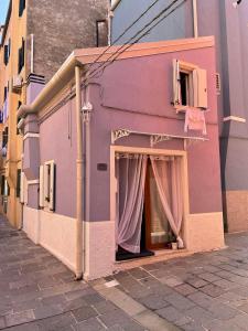 a pink building with a window with a curtain at La dolce dimora in Chioggia