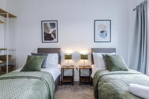 two beds in a room with two lamps at Beautiful Pontefract House w/ Parking Sleeps 12 by PureStay in Pontefract
