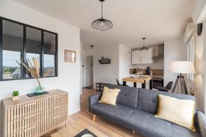 ein Wohnzimmer mit einem Sofa und einer Küche in der Unterkunft Appartement lumineux avec terrasse Saint-Brieuc in Saint-Brieuc