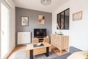 ein Wohnzimmer mit einem TV und einem Tisch in der Unterkunft Appartement lumineux avec terrasse Saint-Brieuc in Saint-Brieuc