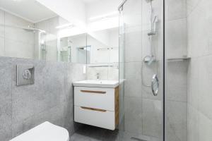 a white bathroom with a shower and a sink at APARTAMENTY przy plaży z basenem z podgrzewaną wodą i mini SPA - Ośrodek Kolonijno-Wczasowy Mewa in Niechorze