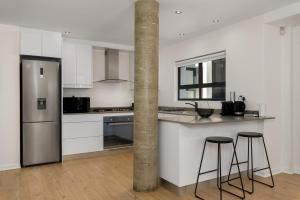 una cucina con frigorifero e 2 sgabelli da bar di Kloof Road Luxury Apartments a Città del Capo