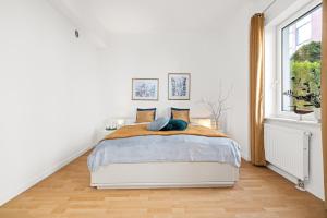 a white bedroom with a bed and a window at Apartament Bursztynowy in Gdańsk