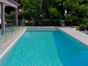 a large blue swimming pool with a wooden deck at Villa De La Brisa - Four Bedroom Villa Sleeps 10 with spectacular sea views in Son Bou