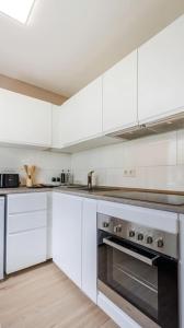 eine Küche mit weißen Schränken und einem Edelstahlofen in der Unterkunft Schöne Wohnung mit Terrasse Nähe Airport in Schönefeld