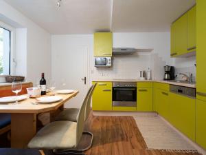 ピーゼンドルフにあるSpecial Apartment in Walchen with Private Terraceのキッチン(ライムグリーンのキャビネット、ワイングラス付きのテーブル付)