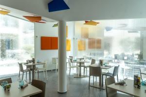 un restaurante con mesas, sillas y ventanas grandes en Residence Continental Resort, en Gabicce Mare