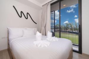 a bedroom with a white bed with a large window at Skypark Laguna BangTao Beach Apartment-Long Term Lease in Phuket Town