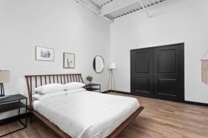 1 dormitorio con cama blanca y puerta negra en CozySuites l Roomy 2BR, Ford Assembly, Indy en Indianápolis