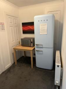 a refrigerator next to a table with a microwave at Aylesford Guesthouse in Kent