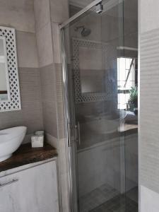 a bathroom with a glass shower and a sink at 19th on Bloekom Guesthouse in Secunda