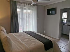 a bedroom with a bed and a large window at 19th on Bloekom Guesthouse in Secunda